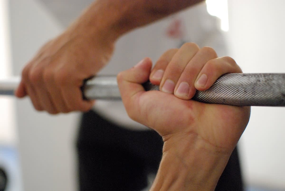 Detailed view of a person's hands gripping a barbell