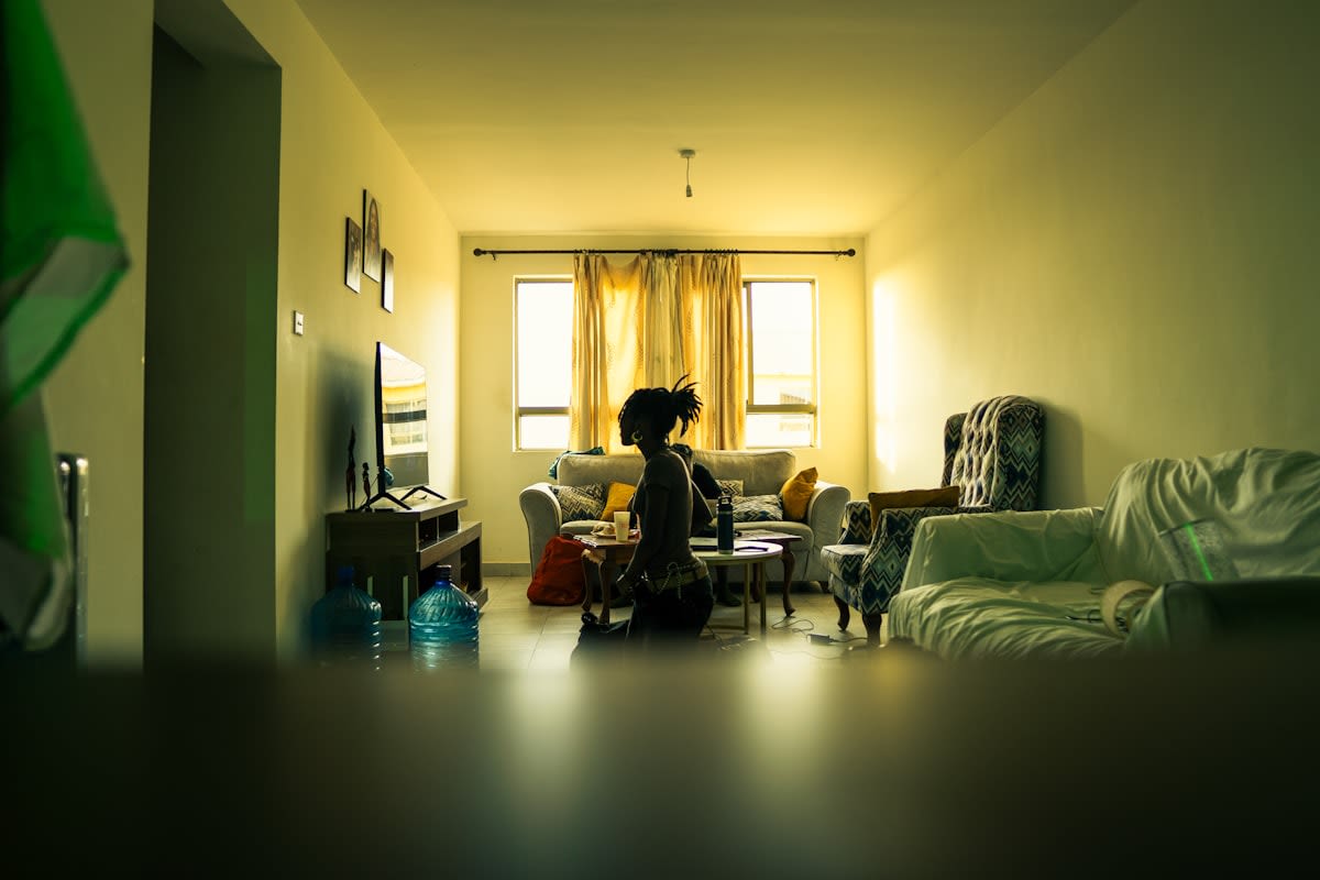 A person sitting in a quiet room with natural light, eyes closed, focusing on the present moment