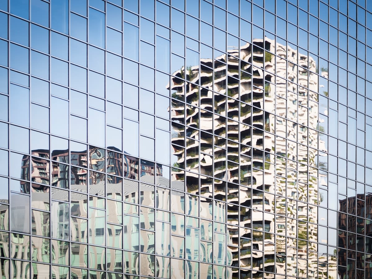 Modern glass skyscraper reflecting a complex city grid