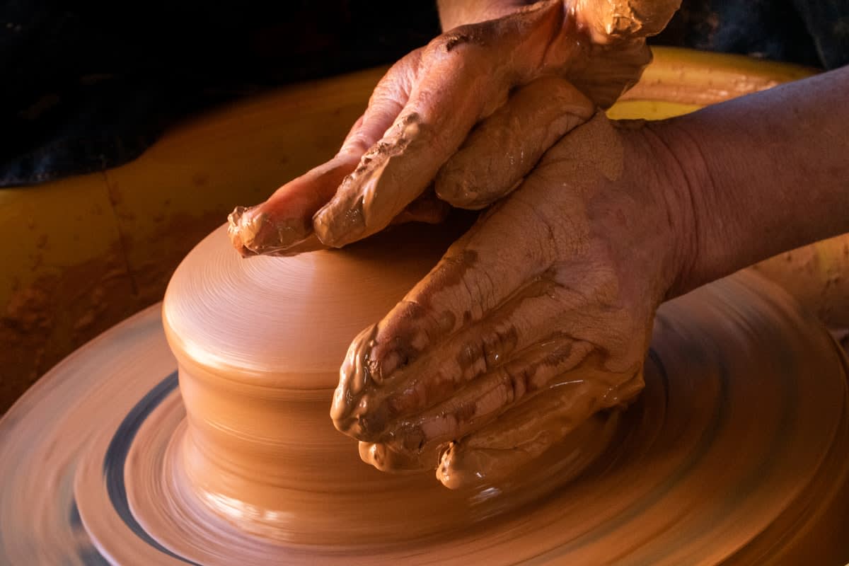 Close up of a potter's hands shaping clay on a wheel