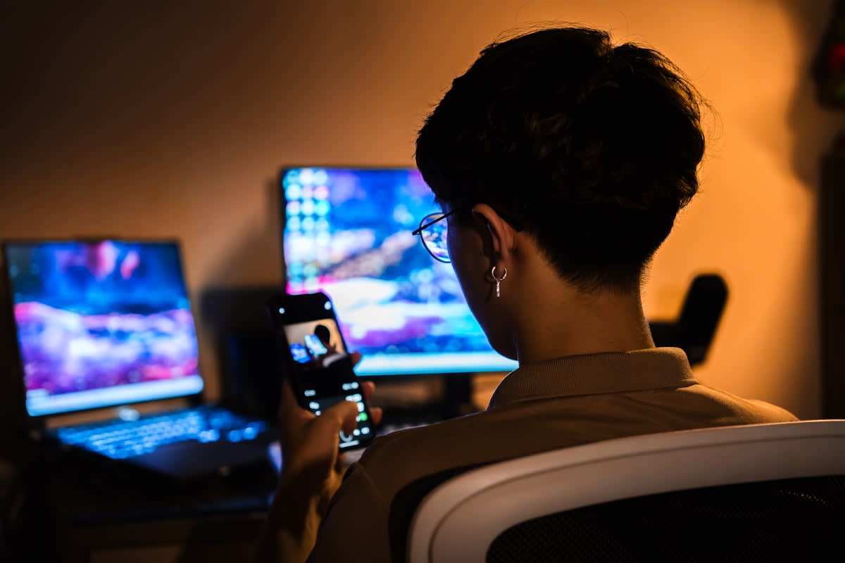 A person looking at multiple screens in a dark room with a soft glow