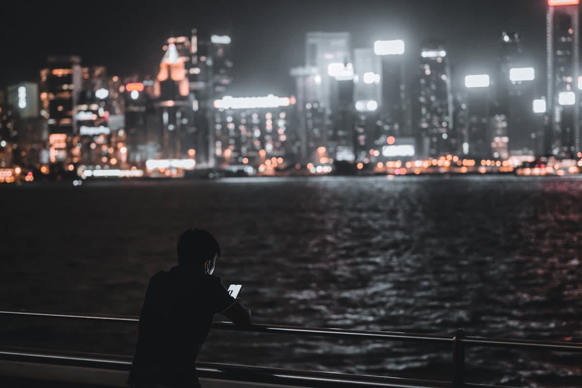 A lonely person looking at a smartphone in a city