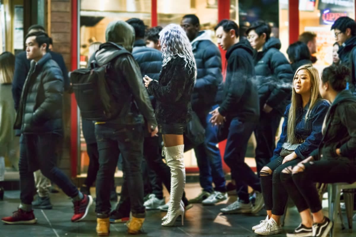 crowd of young people waiting in a long urban queue with smartphones