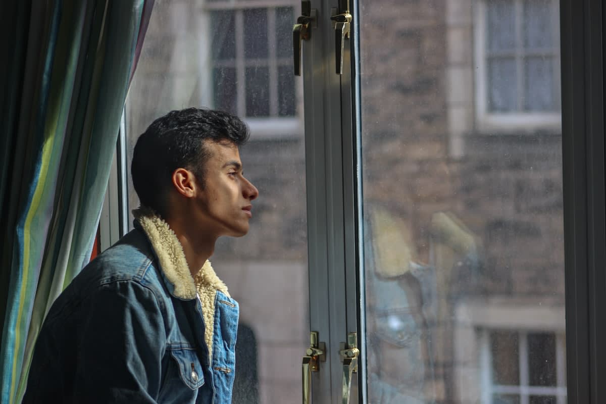 A person standing by a window with bright morning sunlight streaming in