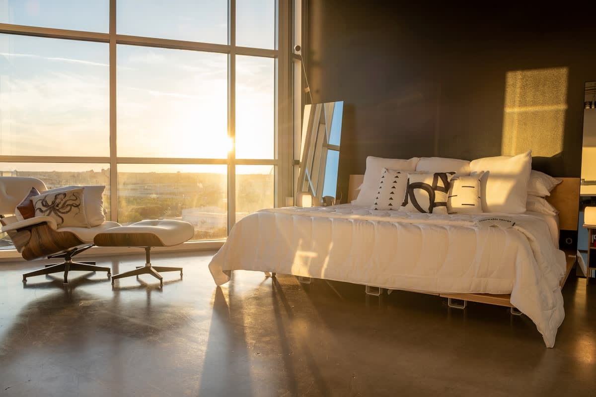 A person waking up to bright morning light in a modern bedroom