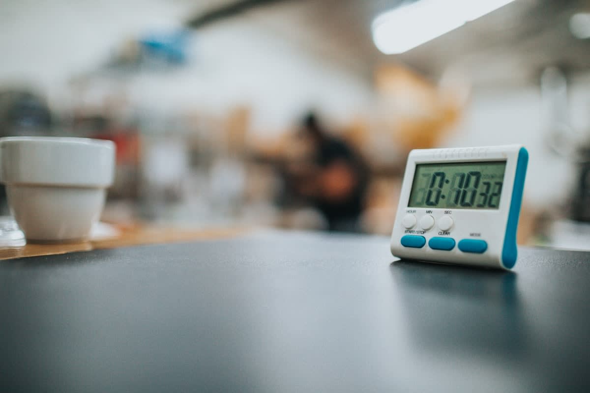 A stopwatch next to a cup of coffee