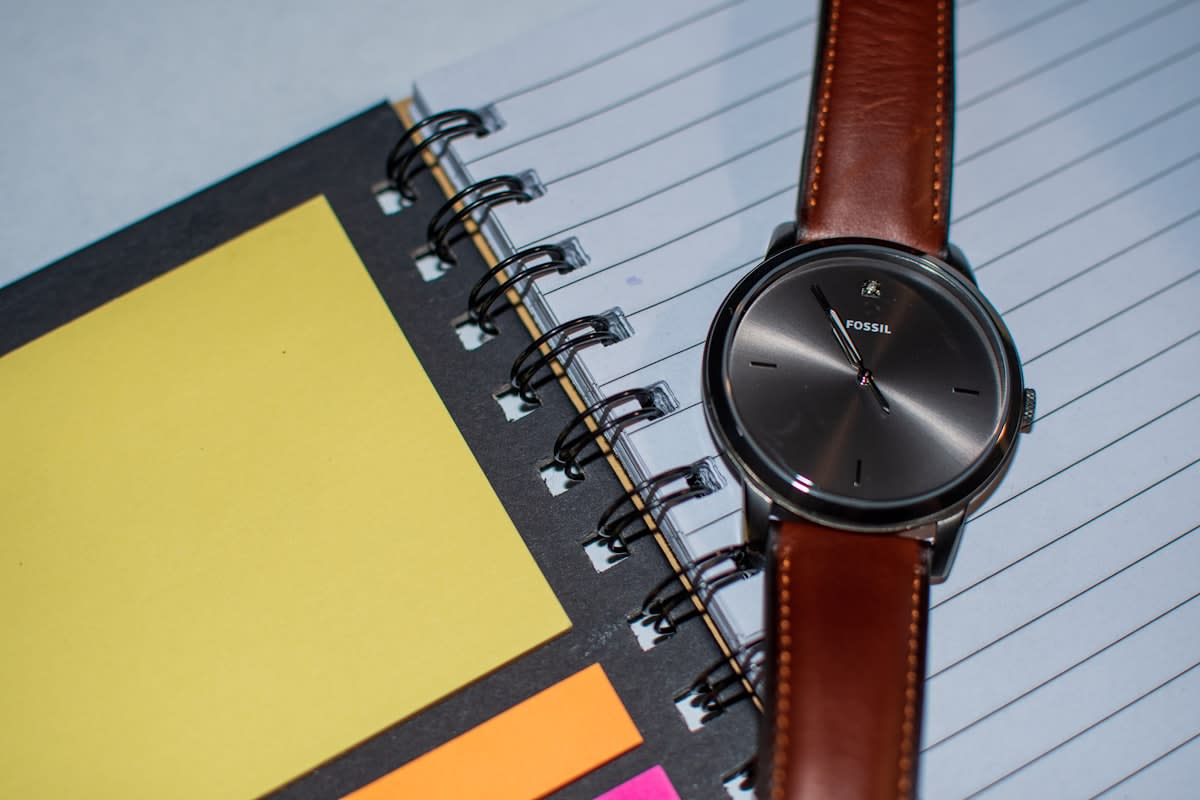 Close up of a high-end analog watch and a simple planner