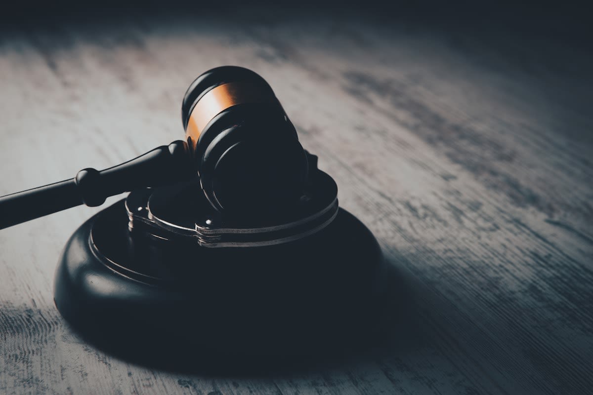 Close up of a legal gavel on a wooden desk with a leaf nearby
