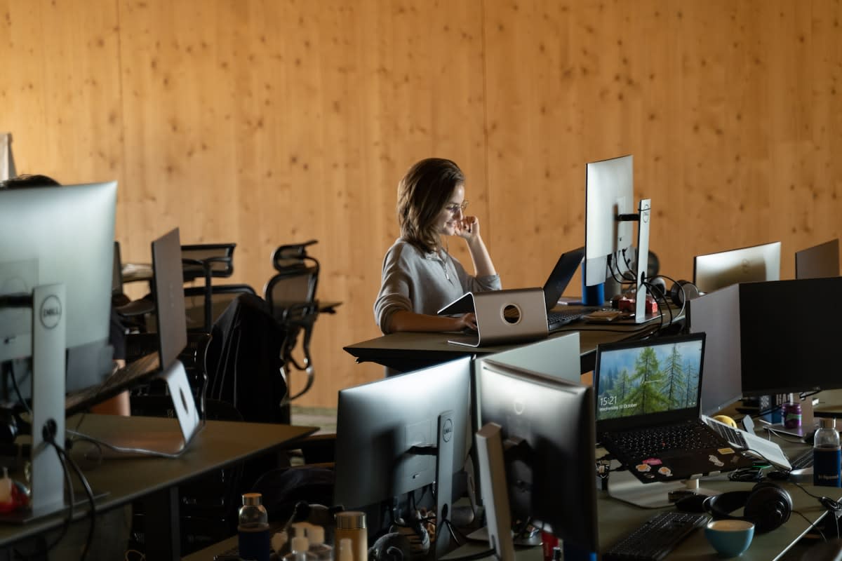 A person sitting calmly at a desk with a single open notebook, contrasted with a cluttered desk with multiple screens