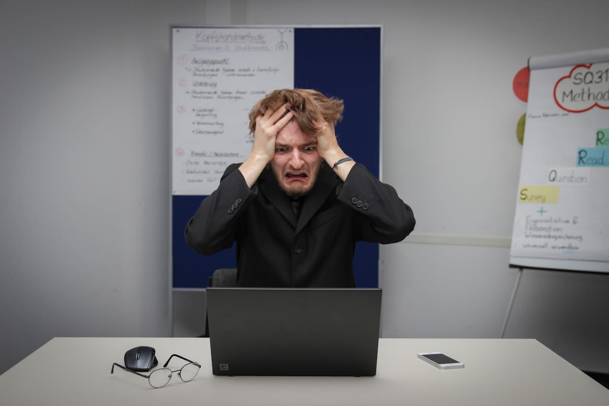 Person looking stressed at a computer screen with many tabs open