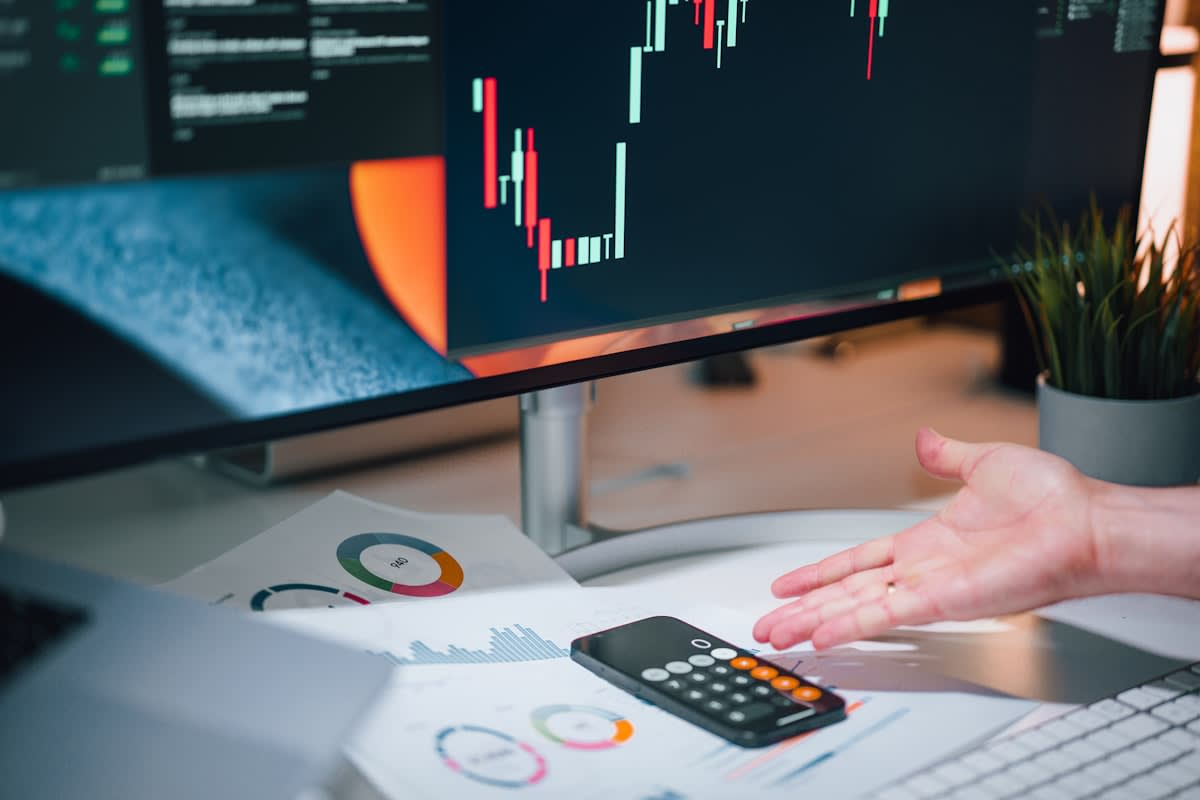 A person working on a complex financial spreadsheet with multiple monitors