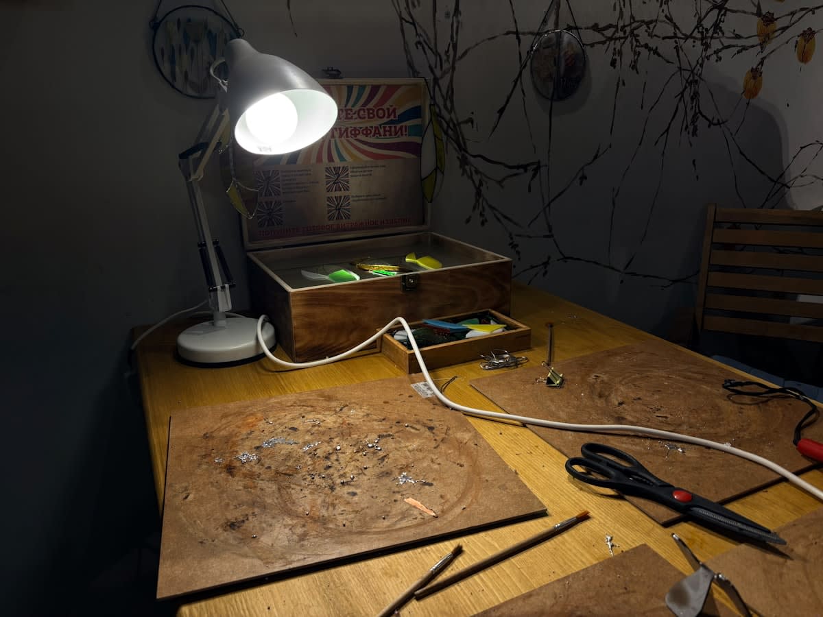 Analog design tools including sketchbooks, charcoal, and physical prototypes on a wooden desk
