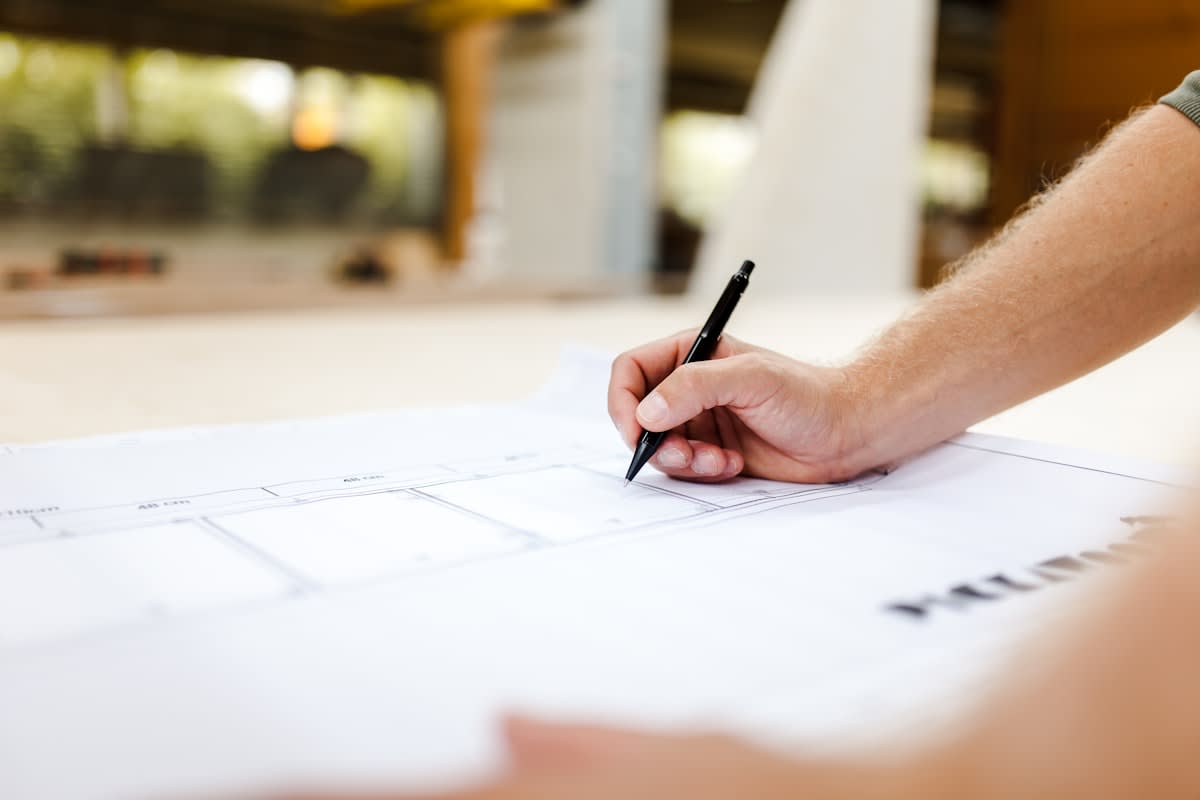 A close-up of a hand sketching a complex architectural diagram on textured paper