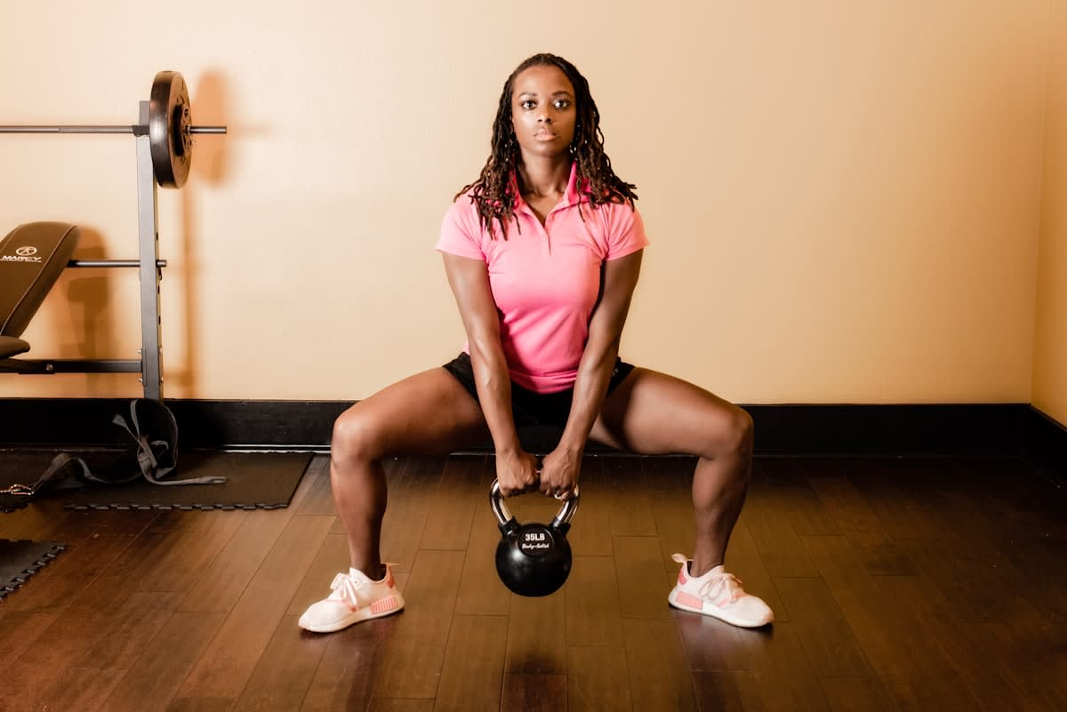 An older adult performing a controlled squat with a kettlebell