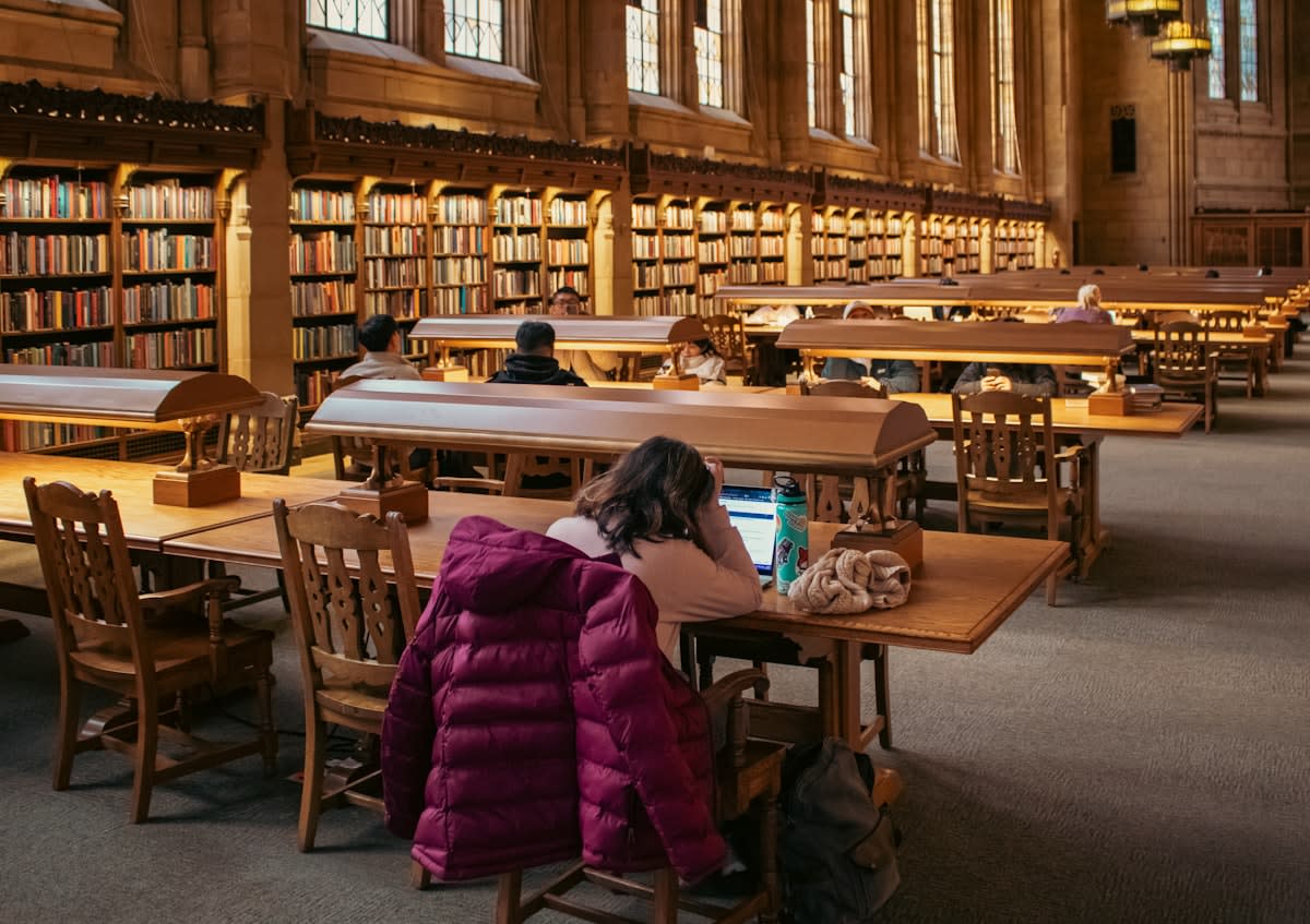 A focused person writing in a notebook in a quiet library