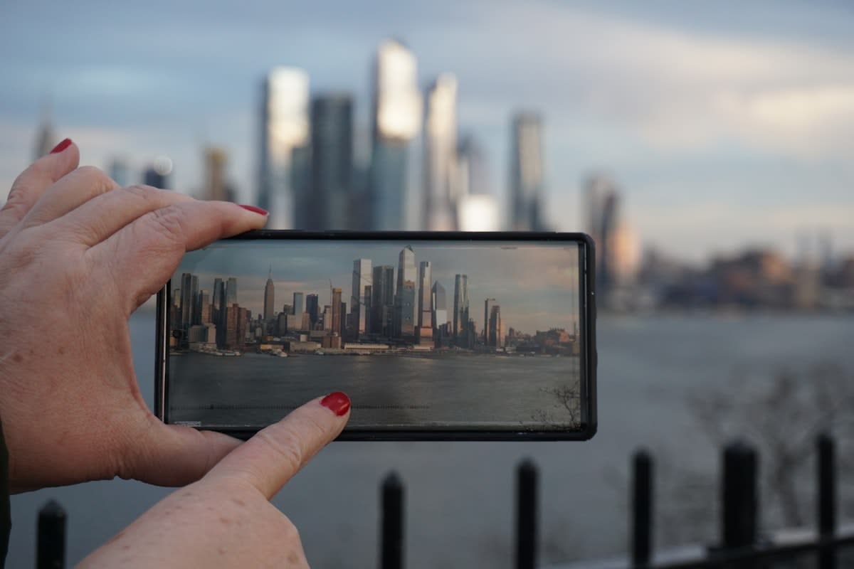 A person holding a smartphone reflecting a distorted image of a city