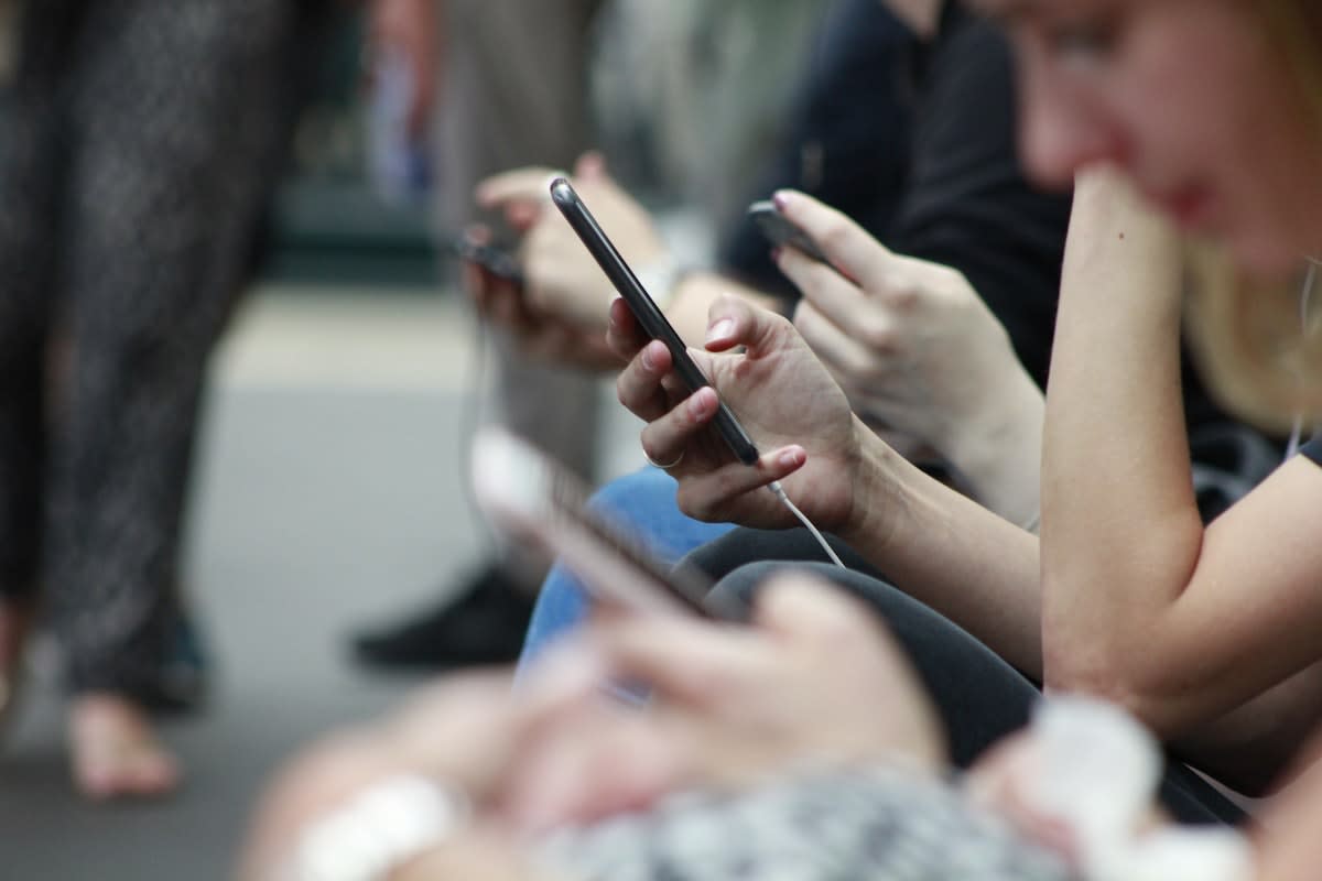 Close up of people using tablets and phones in a social setting