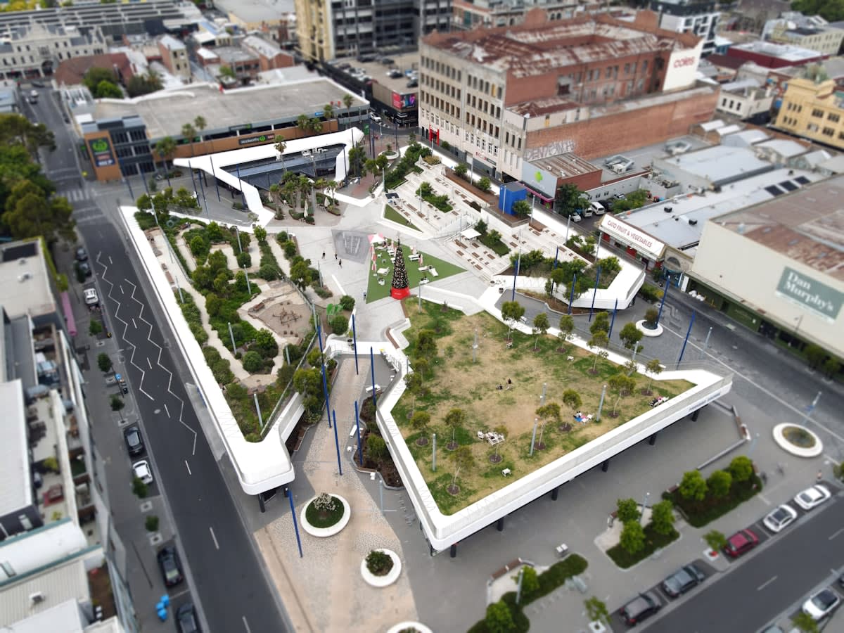 Minimalist urban plaza with integrated greenery and acoustic buffers