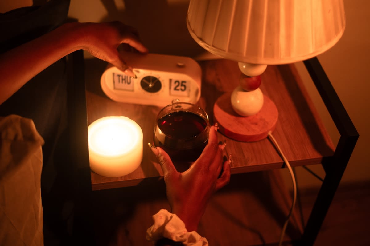 A glass of water with salt and a sunlight lamp on a nightstand