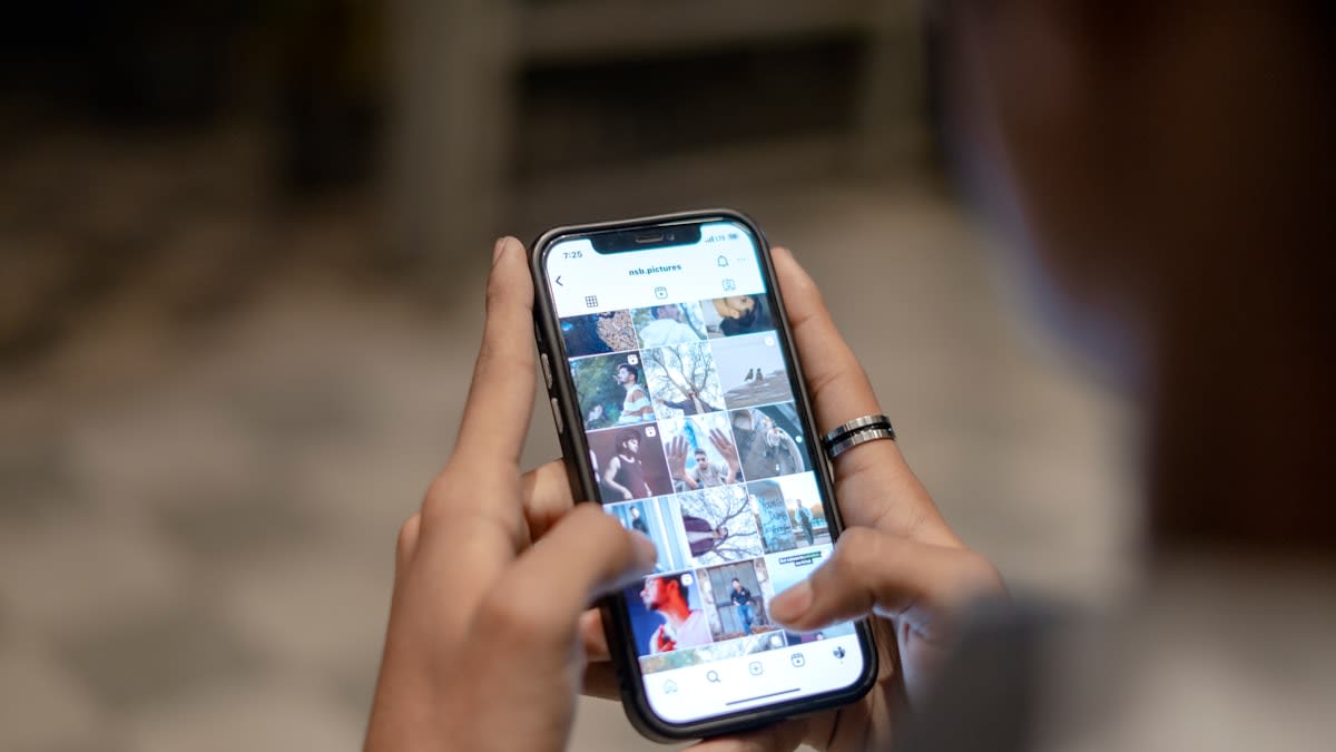 A person looking at a smartphone screen with multiple overlapping social media profiles