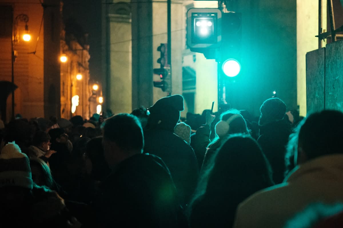 A lonely figure sitting in a crowded urban environment, glowing phone in hand