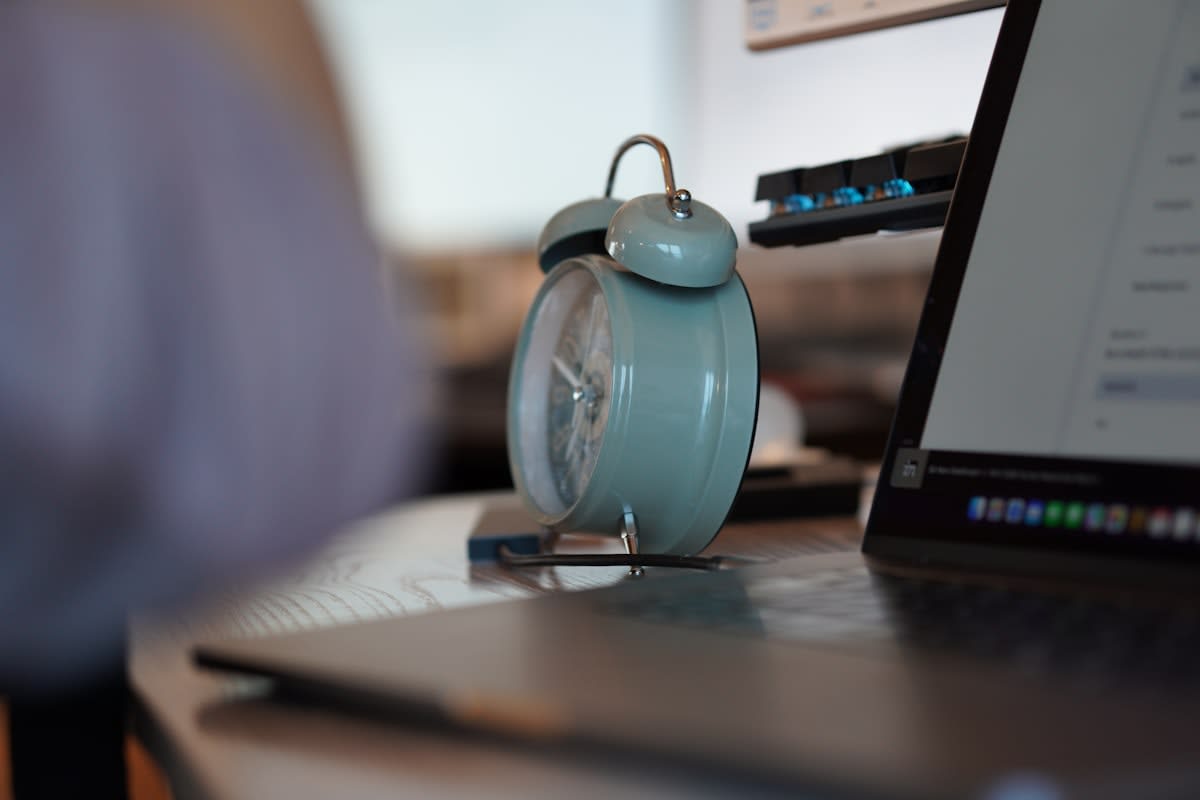 Old industrial clock contrasting with modern digital workspace