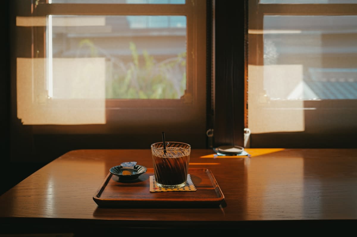 notebook and coffee on a wooden table near a window