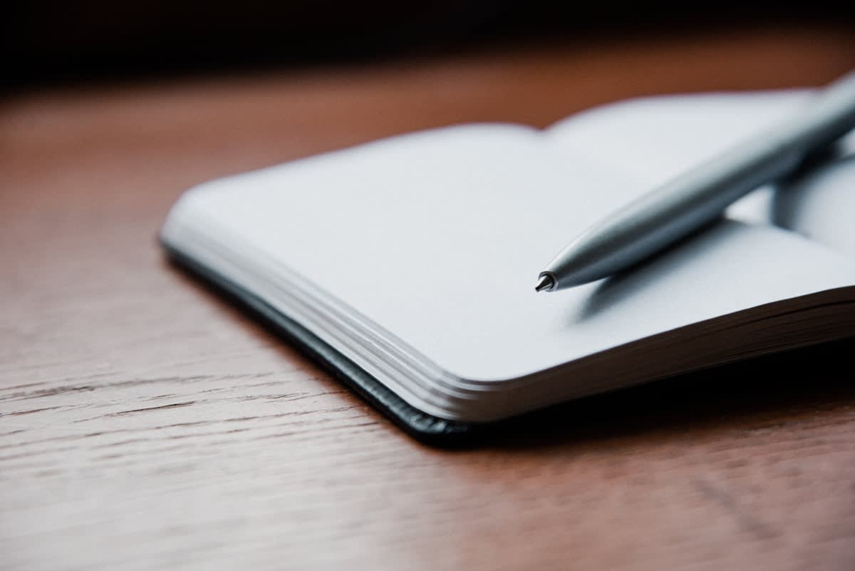 Close up of a journal and a pen on a wooden desk