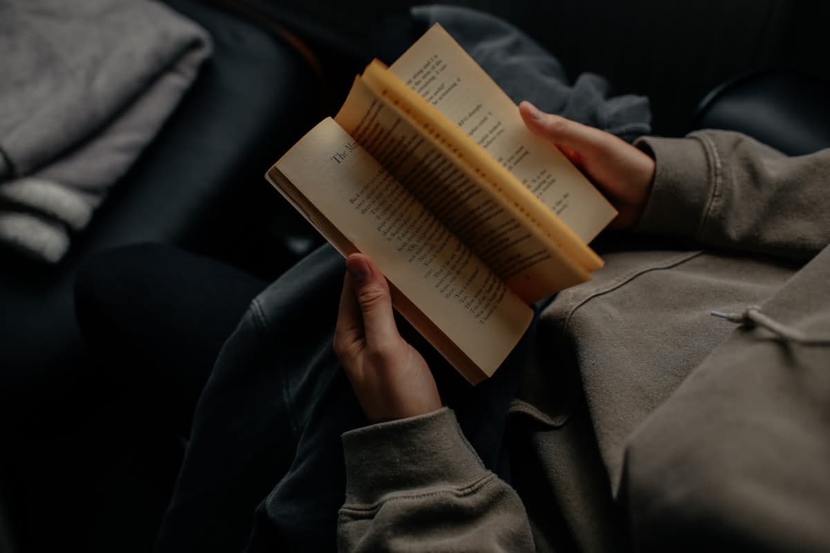A person reading a physical book in a busy, neon-lit city