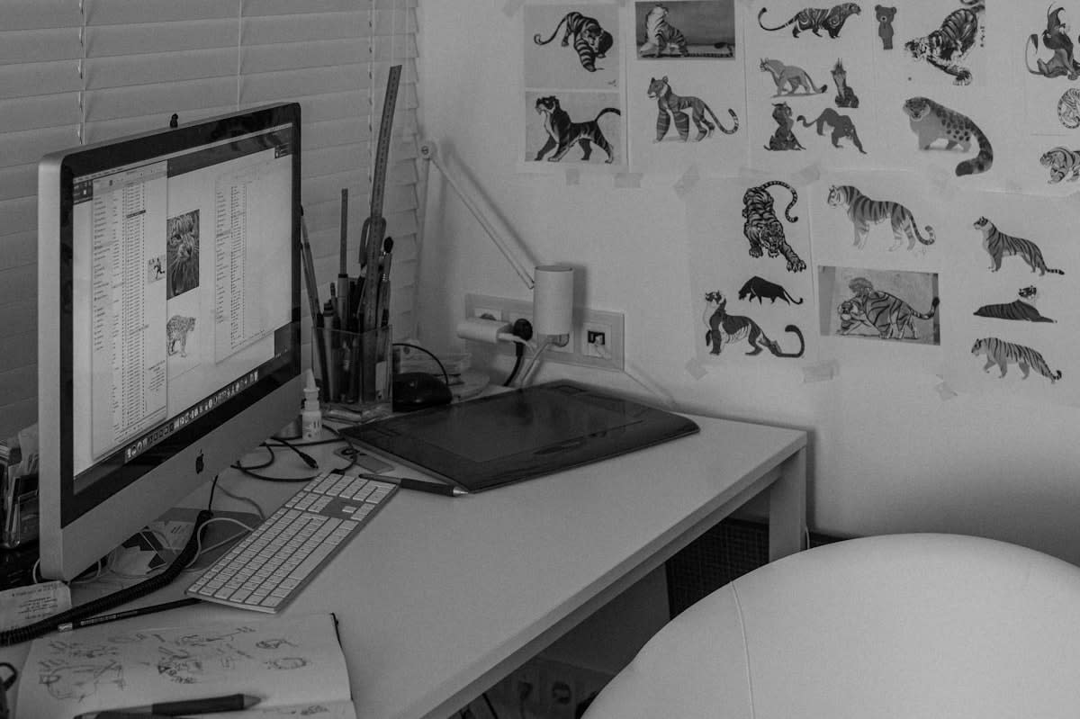 A chaotic artist studio with sketches and analog tools contrasting with a sleek computer screen