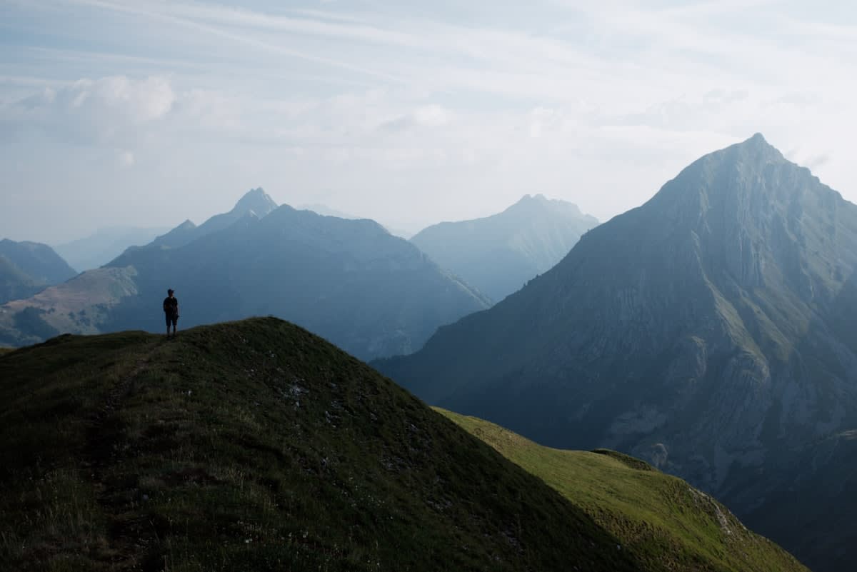 A person standing on a mountain peak looking at a vast, empty horizon