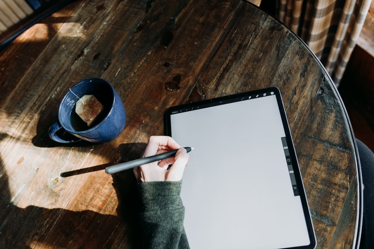 A hand writing in a journal on a wooden table