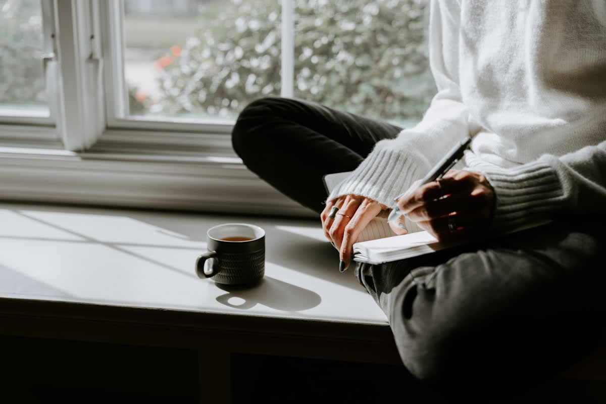 a person sitting peacefully by a window with a cup of coffee
