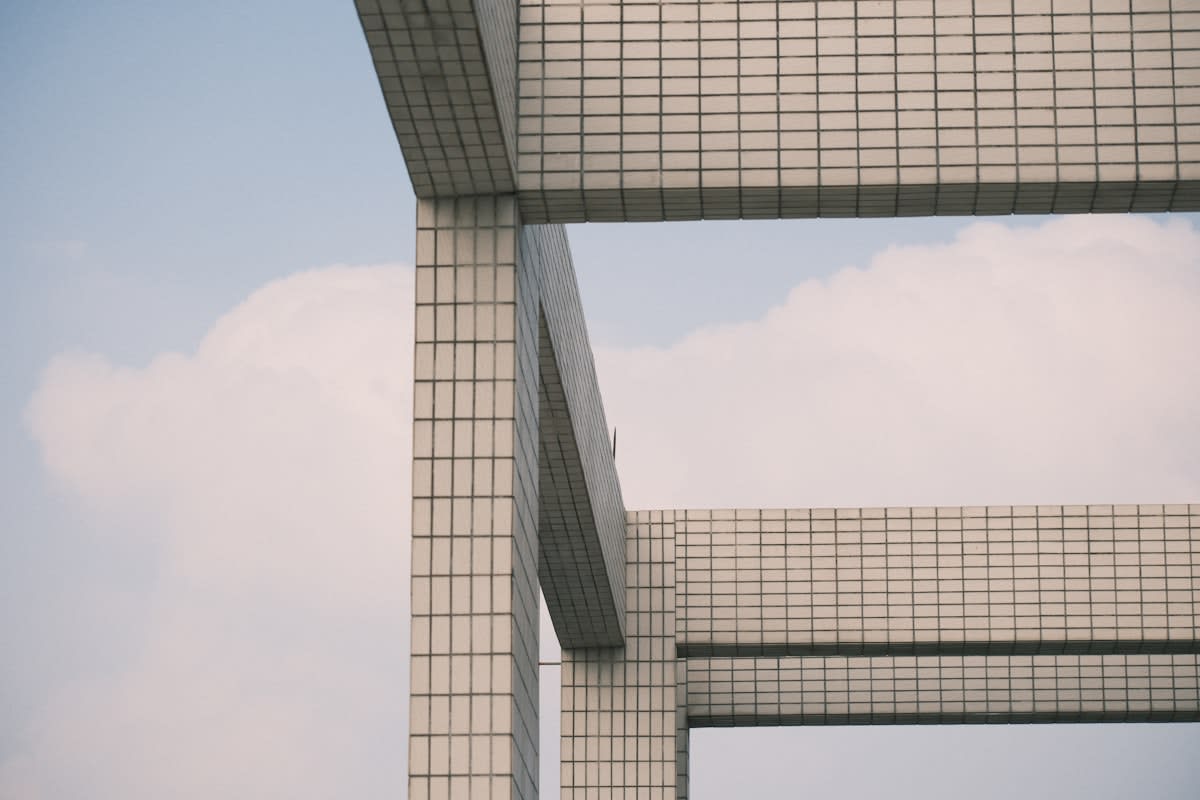 Minimalist architecture showing a single stable pillar amidst moving clouds