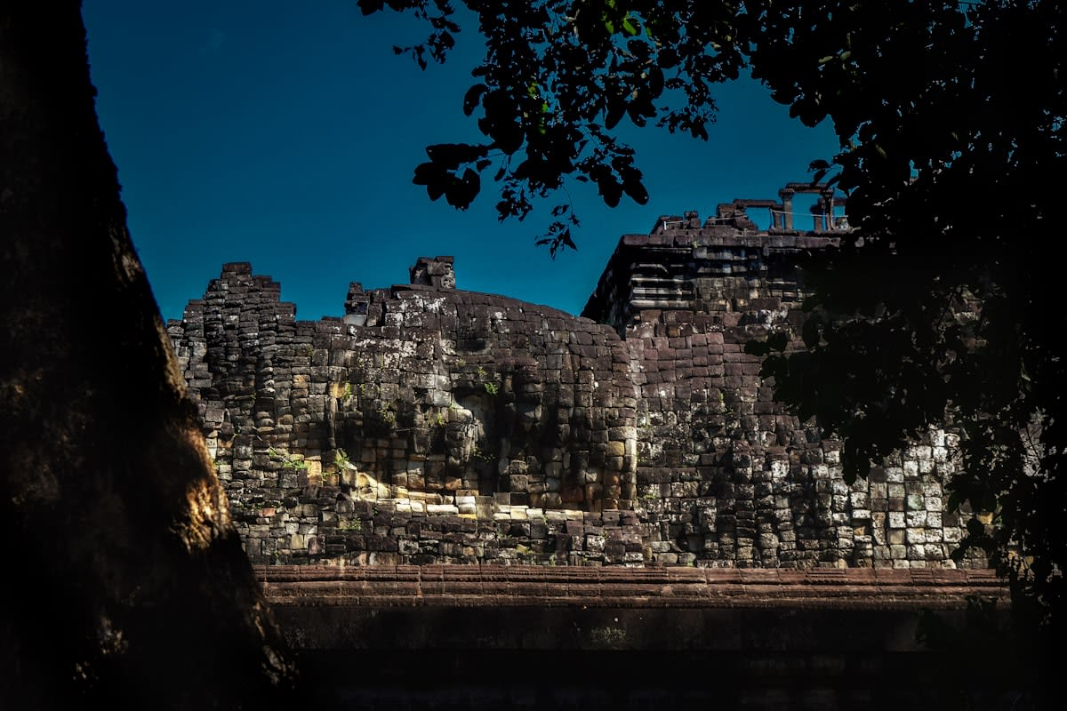 A high-speed train blurring past a stationary, ancient stone temple