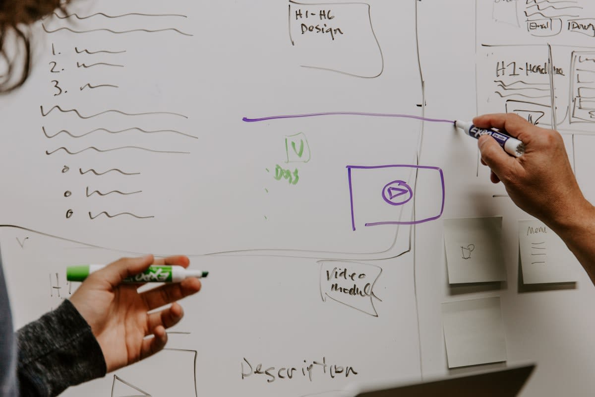 Diverse team collaborating around a whiteboard with mixed diagrams