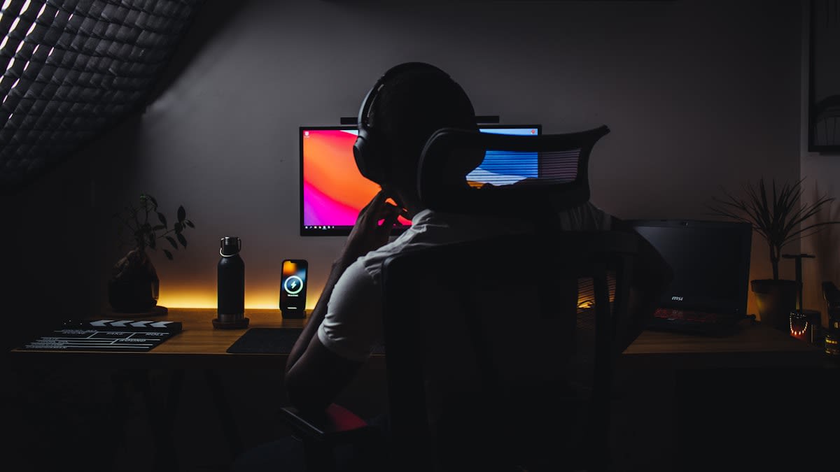 A person resting in a dimly lit, minimalist room with headphones on