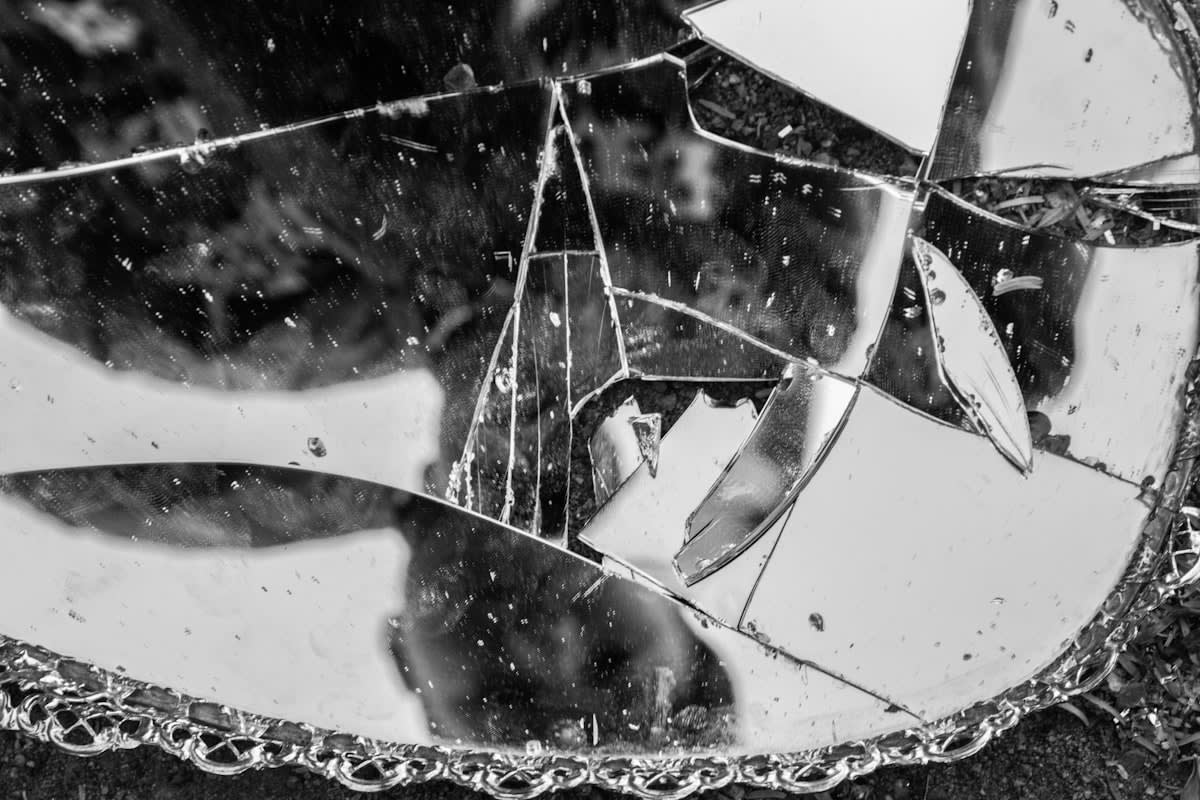 A cracked mirror reflecting multiple fragmented versions of a face
