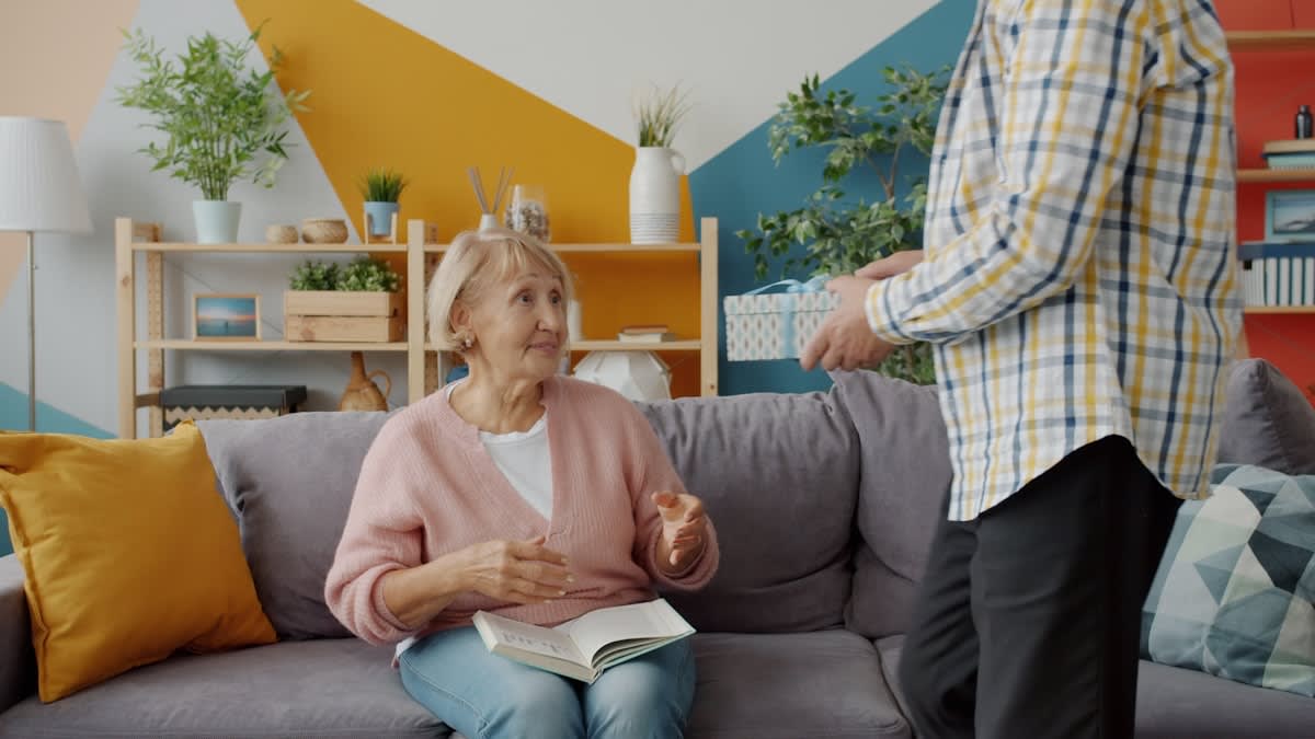 Elderly person and young adult talking in a living room