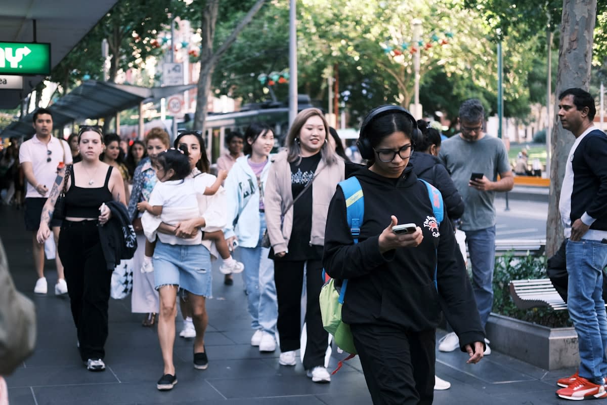 A diverse group of people in an urban setting using smartphones for financial transactions