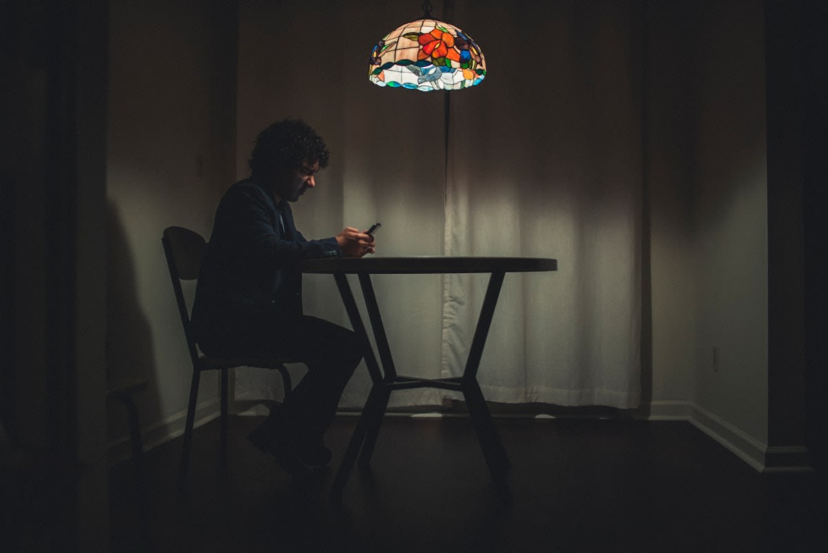 person looking stressed at a smartphone screen in a dark room