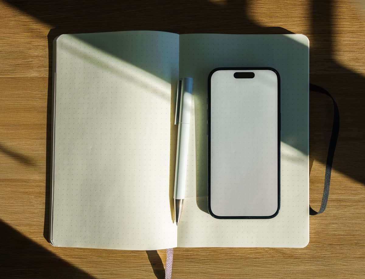 notebook and pen on a clean desk with a phone turned face down