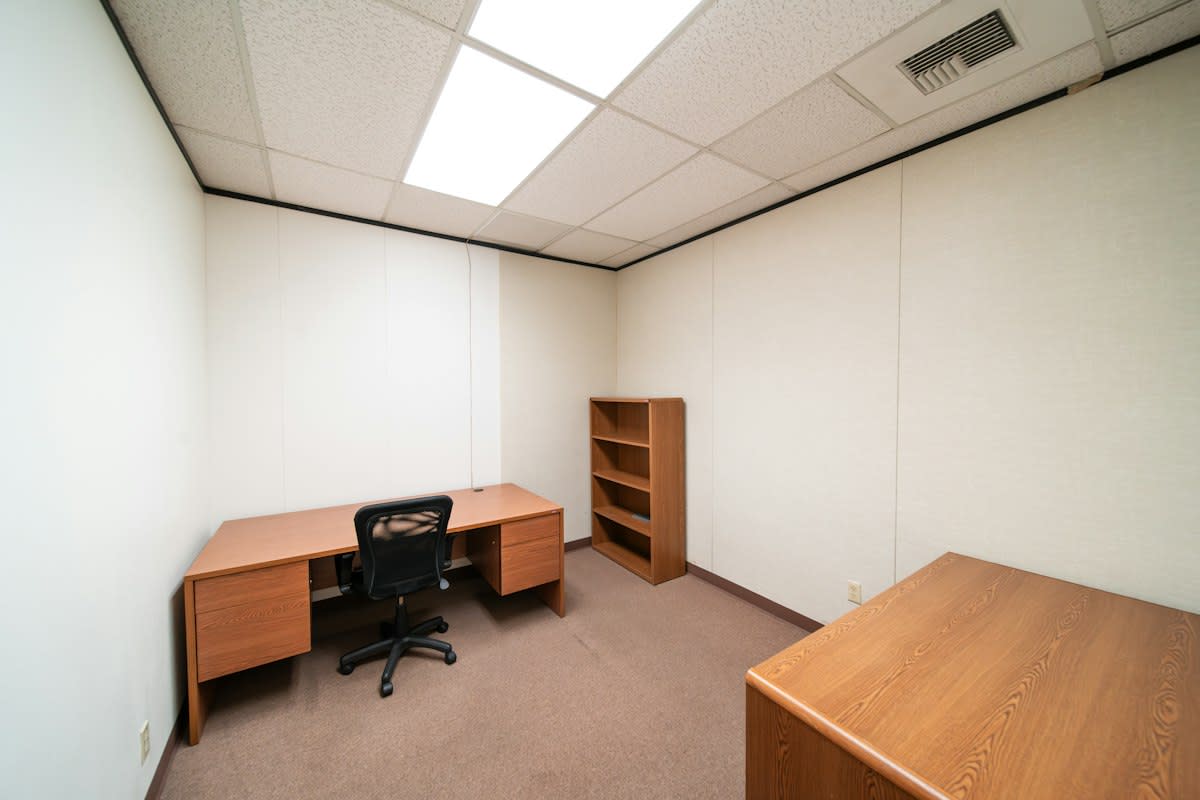 Minimalist corporate office with a single empty desk and a bright window