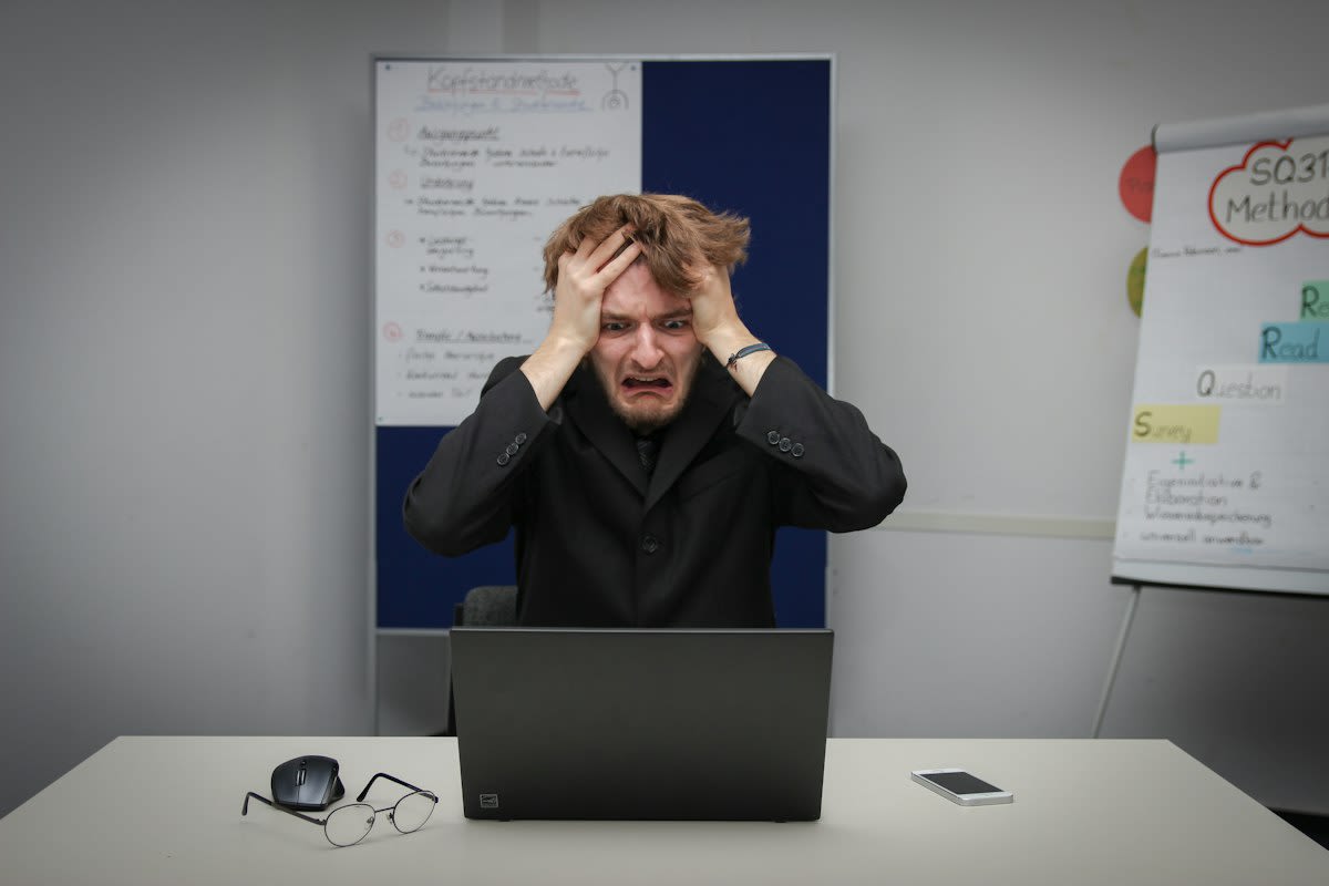 person looking stressed at multiple monitors