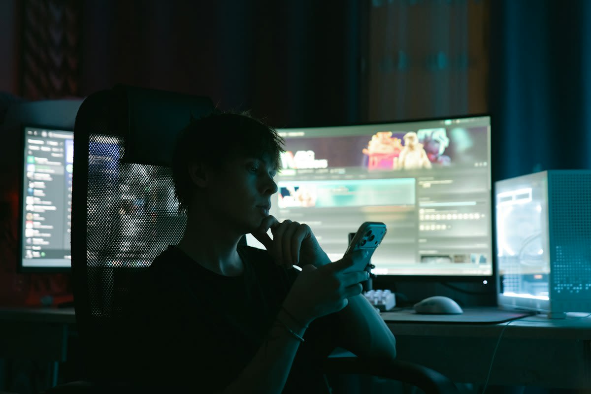 Stressed person looking at multiple computer screens in a dark room