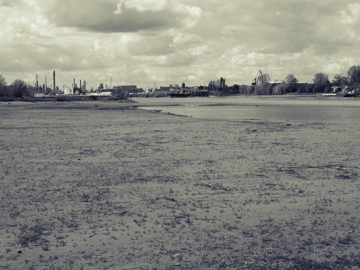 Dried up river bed with industrial infrastructure in background