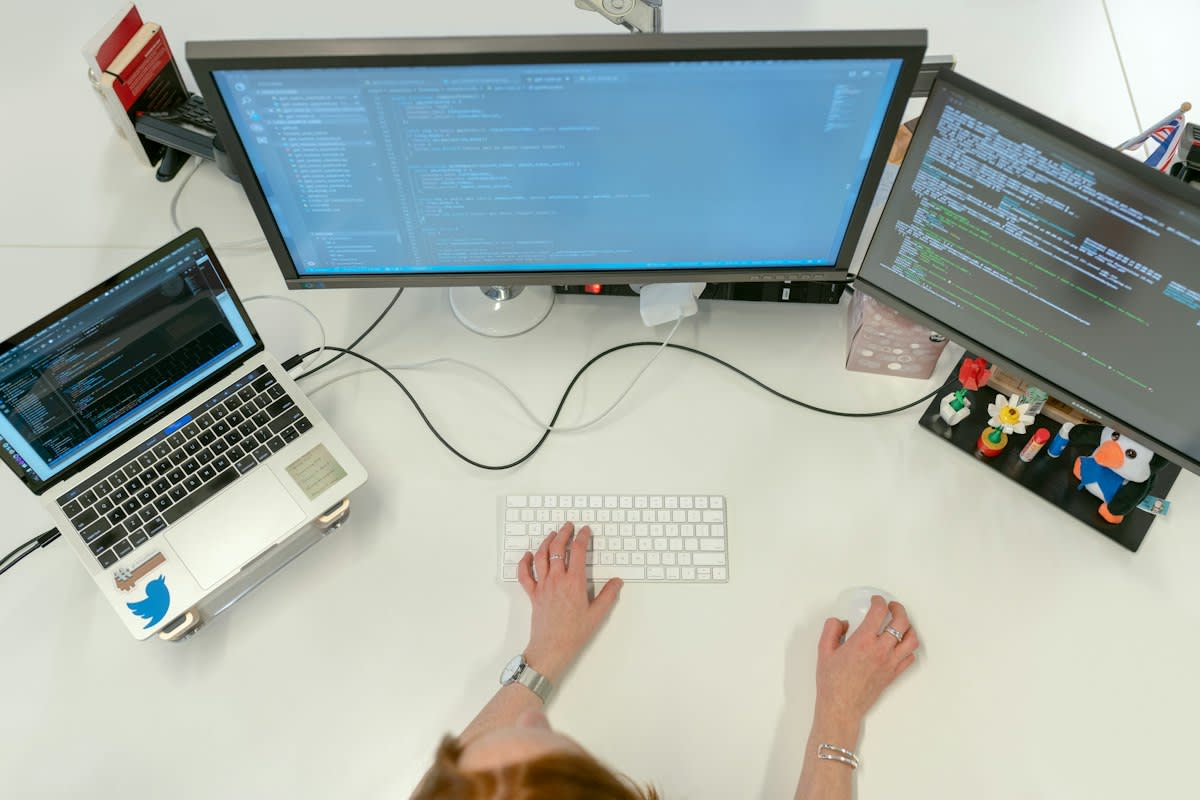 Minimalist high-tech engineering workspace with multiple monitors showing code and documentation