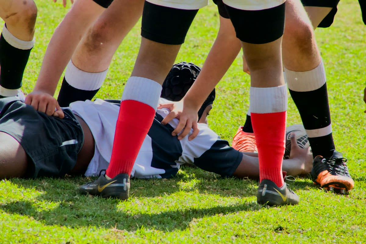 Athletic trainer examining a player's knee on a field
