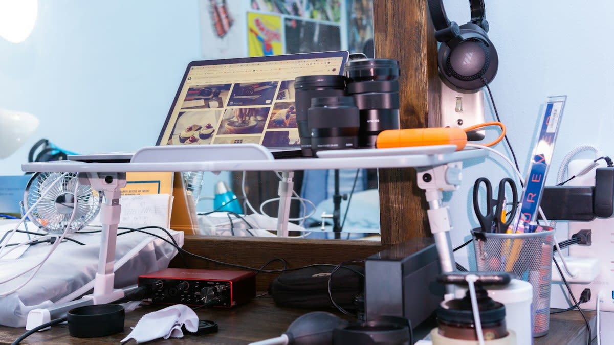 A messy desk with multiple monitors, open computer cases, and wires