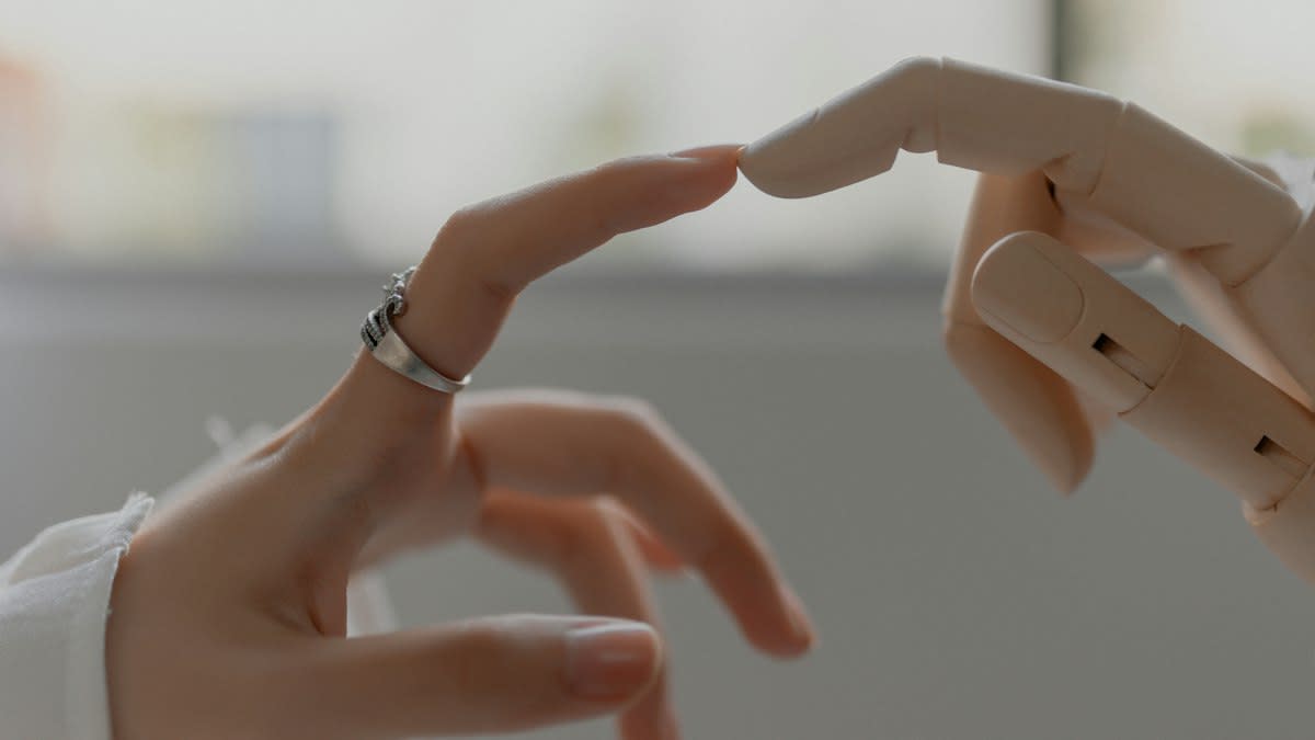 Close up of a robotic hand touching an elderly person's hand